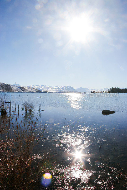 冬日里，新西兰的蒂卡波湖(Lake Tekapo)令人难以置信的清澈碧绿的湖水在天空的阳光下闪闪发光